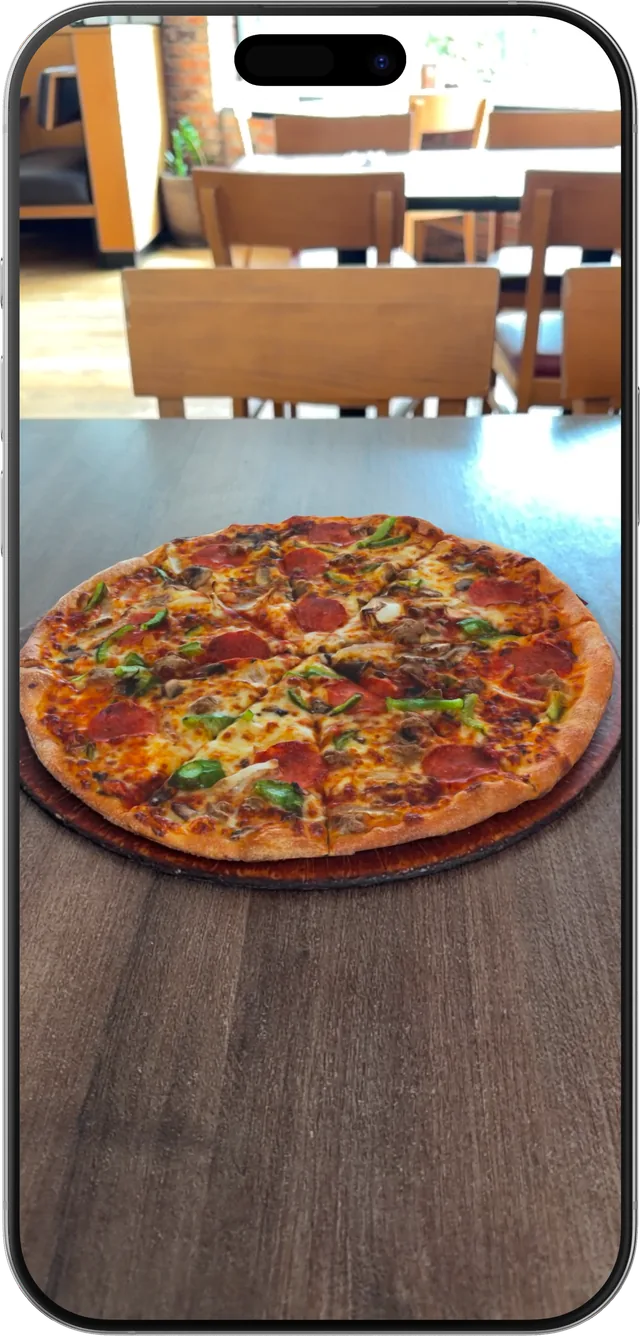 A pizza shown in AR on a restaurant table through a phone